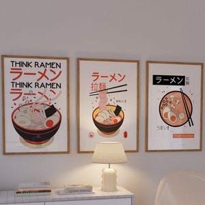 Puede incluir: Tres impresiones enmarcadas con ilustraciones de cuencos de ramen. Las impresiones est&aacute;n en un marco de madera claro con un fondo blanco. El texto en las impresiones dice "Think Ramen", "Ramen", "Ramen", "拉麵", "美味しい!" y "うまい!"