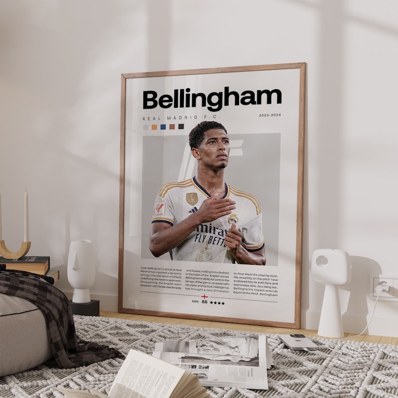 May include: A poster featuring a photo of Jude Bellingham, a soccer player for Real Madrid. The poster has a white background with the text "Bellingham" in black at the top and "REAL MADRID F.C." in smaller black text below. The poster also includes the text "2023-2024" in the top right corner.