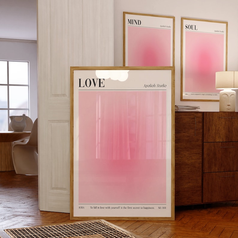May include: Three framed art prints with a soft pink gradient design. The largest print reads "LOVE" at the top, with the text "AURA" and "To fall in love with yourself is the first secret to happiness" at the bottom. Two smaller prints say "MIND" and "SOUL".