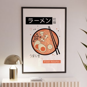 Puede incluir: Un p&oacute;ster enmarcado en negro con una ilustraci&oacute;n roja y blanca de un taz&oacute;n de fideos ramen. El texto en el p&oacute;ster dice "Ramen" en caracteres japoneses y "Fresh Noodles" en ingl&eacute;s.