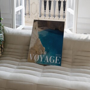 K&ouml;nnte beinhalten: Ein Magazincover mit einem Foto einer t&uuml;rkisblauen Bucht, die von Klippen umgeben ist. Das Magazin tr&auml;gt den Titel "Voyage" mit dem Text "Summer Trip 2023" in kleinerer Schrift.