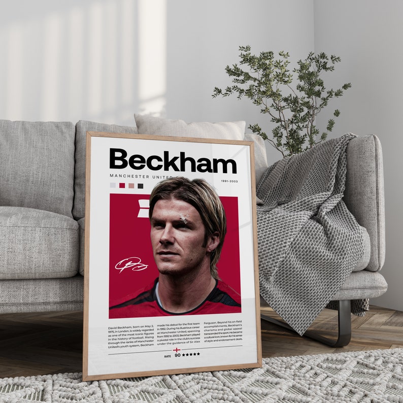 May include: A framed poster with a red background and a photo of David Beckham in a football kit. The poster has the text "Beckham" in large black letters and "Manchester United" in smaller black letters. The poster also includes the years "1991-2003" and a signature.