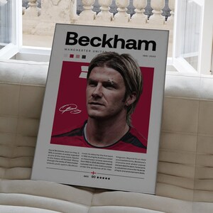 May include: A red and white poster featuring a photo of David Beckham, a former professional footballer. The poster includes the text "Beckham", "Manchester United", and "1991-2003".