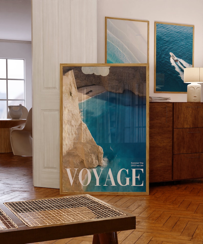 K&ouml;nnte beinhalten: Ein gerahmtes Poster mit einem Foto einer blauen Bucht mit einer felsigen Klippe. Das Poster hat das Wort "VOYAGE" in wei&szlig;en Buchstaben unten und den Text "Summer Trip 2022 July Chris" in kleineren Buchstaben.
