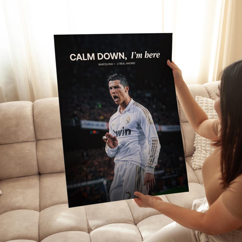May include: A black poster featuring a soccer player in a white jersey. The poster has the text "CALM DOWN, I'm here" and "BARCELONA 1 - 2 REAL MADRID" in white. The player is wearing a jersey with the word "win".