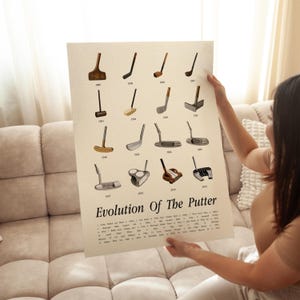 Woman holding evolution of the putter poster vintage golf wall art sitting on sofa.