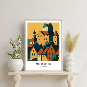 Może przedstawiać: Oprawiony wydruk artystyczny przedstawiający stylizowaną ilustrację miasta Meersburg w Niemczech, z żółtymi, pomarańczowymi i ciemnoturkusowymi budynkami pod żółtym niebem. Napis MEERSBURG GERMANY jest wydrukowany czarną czcionką na dole.