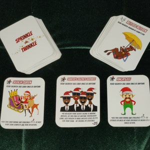 Puede incluir: Una baraja de cartas blancas con ilustraciones y texto con temática navideña. Las cartas presentan imágenes de Papá Noel, elfos y renos, con frases como "Sprinkle the Twinkle" e instrucciones.