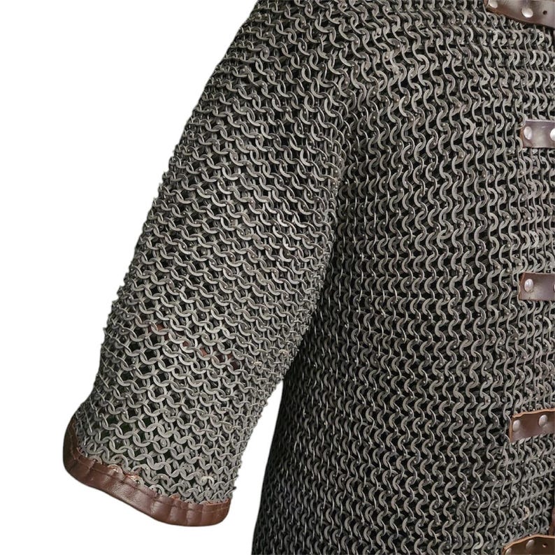 May include: A close-up of a chainmail shirt with brown leather trim. The shirt is made of interlocking metal rings and has a textured surface.