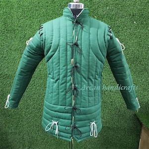 May include: A green quilted jacket with black lacing and white ties. The jacket has a high collar and long sleeves. The jacket is made of a thick, durable fabric and is designed for protection.