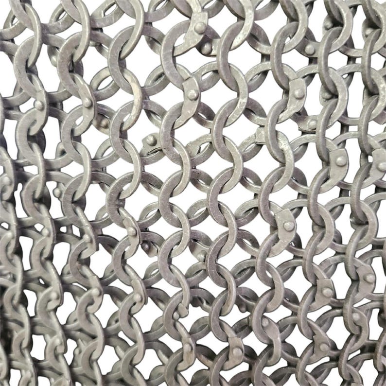 May include: Close-up of a silver chainmail, a type of armor made of interlocking metal rings.