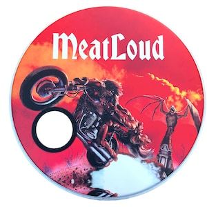 May include: A red drumhead featuring a white graphic of a motorcyclist and a winged demon. The text "MeatLoud" is printed in white at the top of the drumhead.