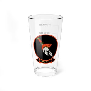 May include: A clear glass pint glass with a black and orange graphic of a Spartan helmet and spear. The text "VFA-147" is printed below the graphic.