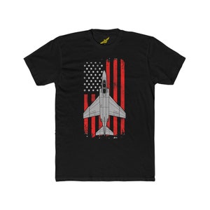 May include: Black t-shirt featuring a distressed American flag design with a grey fighter jet in the centre.