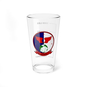 May include: A clear glass pint glass with a white printed design. The design features a red, white, and blue emblem with a globe and wings. The text "HELSUPRRON 3" is printed below the emblem. The glass has markings for 3000 lbs and 2000 lbs.