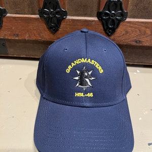 May include: A navy blue baseball cap with a yellow embroidered logo that says "Grandmasters" and "HSL-46".