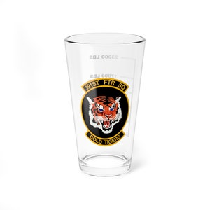 May include: A clear glass pint glass with a white graphic of a tiger's head with blue eyes. The graphic includes the text "391ST FTR SQ" and "BOLD TIGERS".