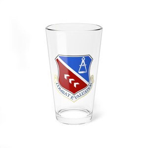May include: A clear glass pint glass with a red, white, and blue shield design. The shield has a compass and three red arrows. The text "COMBAT EVALUATION" is written in a gold banner around the shield.