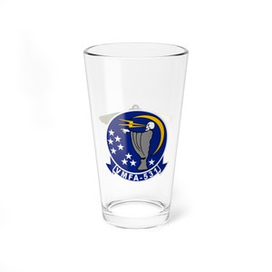 May include: A clear glass pint glass featuring a blue and yellow graphic of a skull with a lightning bolt and crescent moon. The graphic also includes the text "VMFA-531".