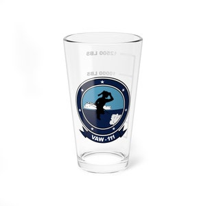 Op de afbeelding: Een helder glazen pintglas met een donkerblauw en wit squadroninsigne met een silhouet van een vrouw die door een verrekijker kijkt. Het insigne heeft de tekst "VAW-111".