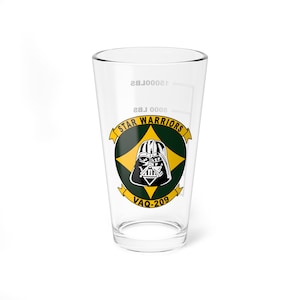 May include: A clear glass pint glass with a green and yellow emblem featuring a Darth Vader illustration and the text "STAR WARRIORS VAQ-209".