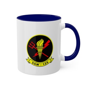 May include: White ceramic coffee mug with a blue rim and handle. The mug features a black and yellow squadron insignia with a red trident, lightning bolt, and torch. The text "VAW - 125" is printed below the insignia.