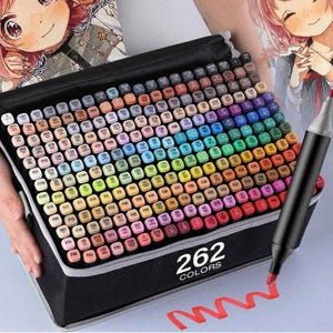 May include: A black carrying case containing 262 dual-tip markers arranged in a grid, each cap labelled with a colour code. A single black marker with a red tip is positioned to the right, drawing a red wavy line on the surface below the case.
