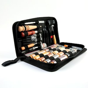 Puede incluir: Un estuche negro con cremallera, abierto para revelar un kit de herramientas para manualidades en cuero. El kit incluye varias herramientas con mangos de madera y metal, junto con carretes de hilo de varios colores. Las herramientas est&aacute;n bien organizadas dentro del estuche.