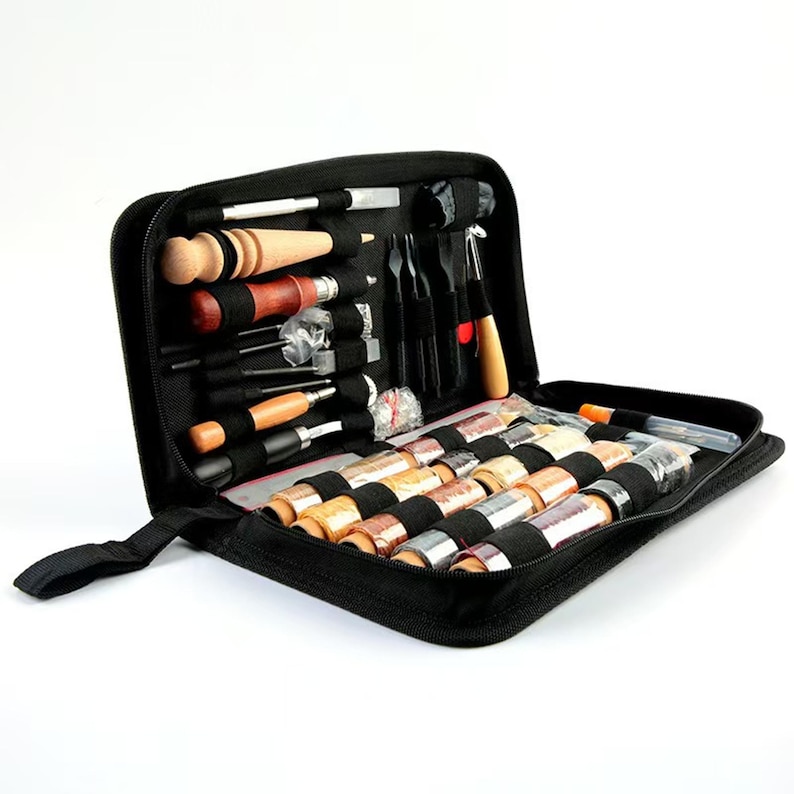 Puede incluir: Un estuche negro con cremallera, abierto para revelar un kit de herramientas para manualidades en cuero. El kit incluye varias herramientas con mangos de madera y metal, junto con carretes de hilo de varios colores. Las herramientas est&aacute;n bien organizadas dentro del estuche.