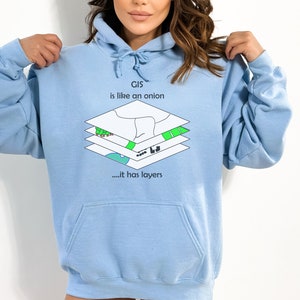 Pode incluir: Camisola de capuz azul claro com uma estampa gráfica de um mapa em camadas e o texto "GIS is like an onion... it has layers".