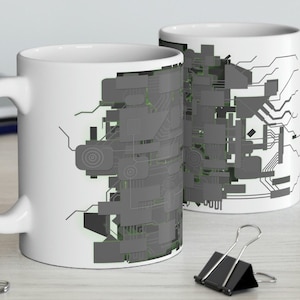 May include: Two white ceramic mugs with a gray and green circuit board design. The mugs are on a light wood surface.