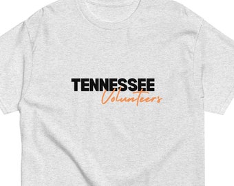 May include: A light gray t-shirt with the words "TENNESSEE" in black and "Volunteers" in orange. The shirt is made of a soft material and has a classic crew neck design.