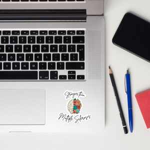 Op de afbeelding: Een sticker met een illustratie van een brein met bloemen die eruit groeien. De tekst "Stranger than Multiple Sclerosis" staat onder het brein.