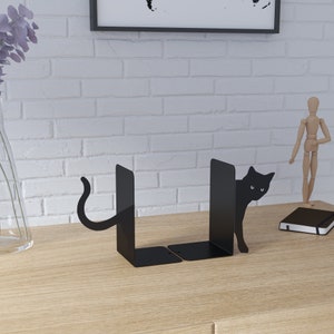 May include: Black metal bookends shaped like a cat peeking out from behind the books. The cat's tail is curled around the back of the bookend.