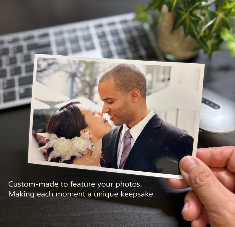 May include: A rectangular photograph showing a person with dark hair wearing a white floral hair accessory and a person in a dark suit with a white shirt and striped tie. The text reads: Custom-made to feature your photos. Making each moment a unique keepsake.
