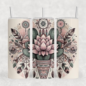 May include: A set of three insulated tumblers with a decorative design. The design features a central cactus and lotus flower arrangement, surrounded by feathers, dream catchers, and geometric patterns in shades of pink, brown, and green. Each tumbler has a silver straw.