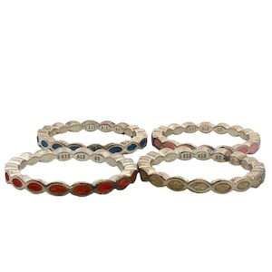 May include: Four sterling silver stackable rings, each featuring a repeating marquise-shaped enamel inlay. The rings are colored in red, blue, pink, and a neutral beige tone. Each band is stamped with the hallmark S925 ALE and the size 60.