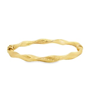 May include: A polished gold bangle bracelet featuring a continuous twisted, undulating design. The metal surface alternates between smooth, reflective sections and finely grooved, textured segments, complete with a secure hinged clasp mechanism.