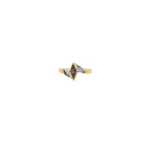 May include: A gold ring featuring a central marquise-cut purple gemstone set in a diamond-shaped frame. The band transitions into a silver-toned metal section on both sides, which is embellished with small, clear, sparkling accent stones.