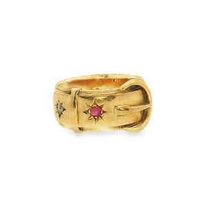 May include: A gold ring designed to resemble a belt with a buckle closure. The band features a textured edge and is set with a central round red gemstone and a smaller clear gemstone, each surrounded by an engraved starburst pattern on the surface.