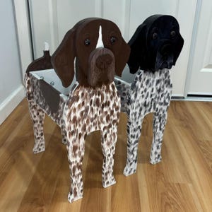 May include: Two wooden dog-shaped planters featuring detailed painted coats. One planter has a brown and white spotted pattern with a solid brown head, while the other has a black and white spotted pattern with a solid black head and ears.