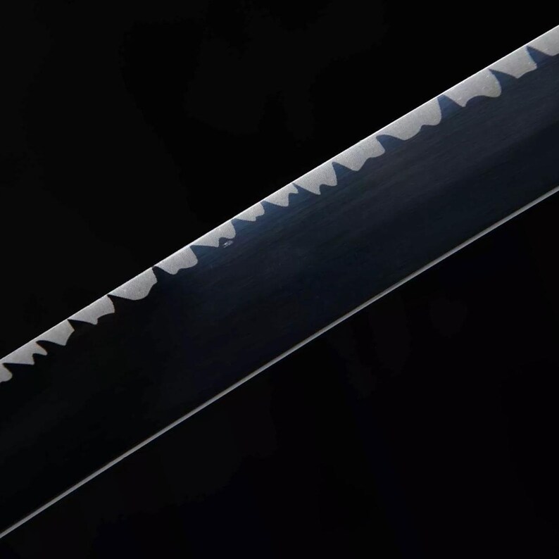 May include: Close-up of a black sword blade with a serrated edge. The blade has a dark, reflective surface, and the serrations are a lighter color, creating a contrast against the black background. The image is well-lit, highlighting the blade's details.