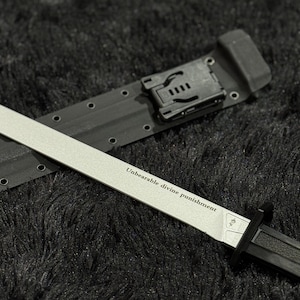Könnte beinhalten: Ein silbernes und schwarzes Messer mit dem Text "Unbearable divine punishment" auf der Klinge. Das Messer befindet sich in einer schwarzen Scheide mit einem Gürtelclip. Der Hintergrund ist eine dunkle, strukturierte Oberfläche.