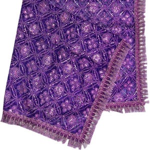 May include: Purple sequined table runner with a fringe border. The runner has a geometric pattern and is made of a soft, luxurious fabric.