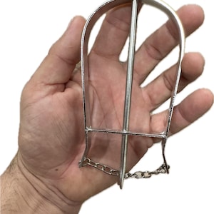 May include: A silver metal animal trap with a pointed end and a chain. The trap is designed to catch small animals.