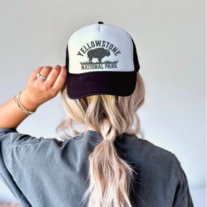 May include: Black and white trucker hat with a white logo that says "Yellowstone National Park" and a silhouette of a bison.