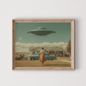 May include: Framed print featuring a retro-style scene with a teal flying saucer hovering over a house and a vintage car. A person stands in the foreground, gazing upwards. The artwork has a vintage aesthetic with muted colors.