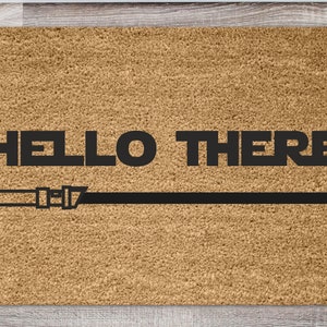 May include: A brown coir doormat with the text "HELLO THERE" in black lettering and a black lightsaber graphic.
