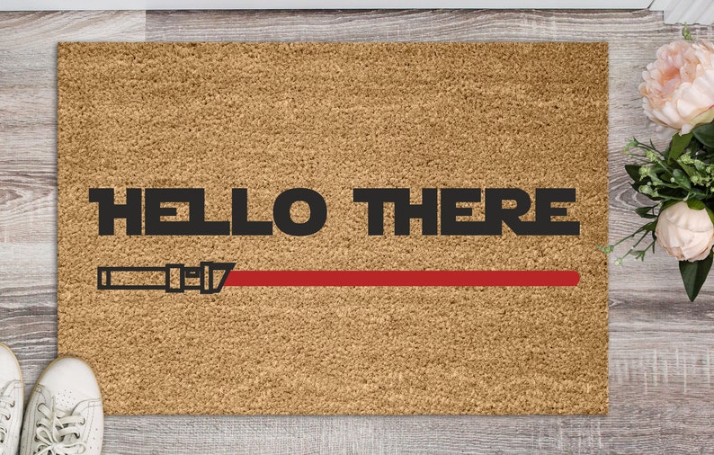 May include: A brown doormat with the text "HELLO THERE" in black letters and a red lightsaber graphic.