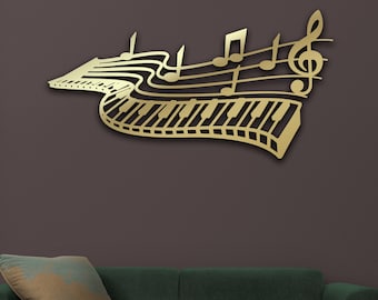 May include: A gold metal wall decor featuring a musical note design with a piano keyboard. The decor is mounted on a dark gray wall above a green sofa with a pillow.